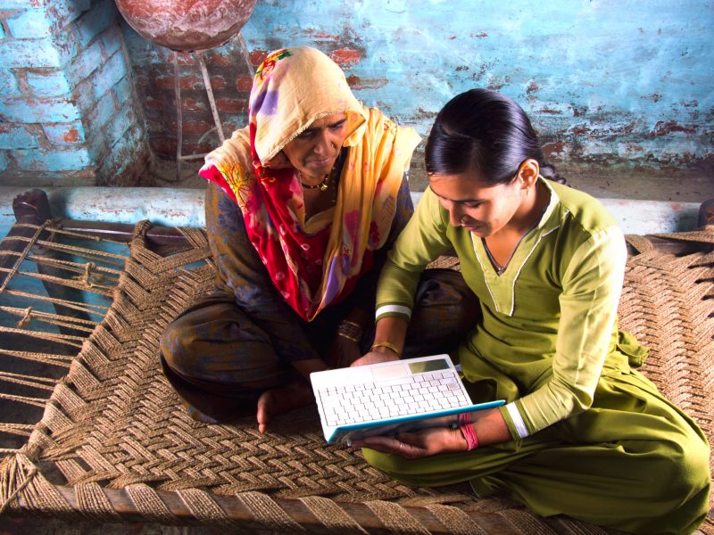 Village Women Working on Laptop with her Younger Daughter and Sitting on Charpai. The Shot is Taken using Studio Lights.